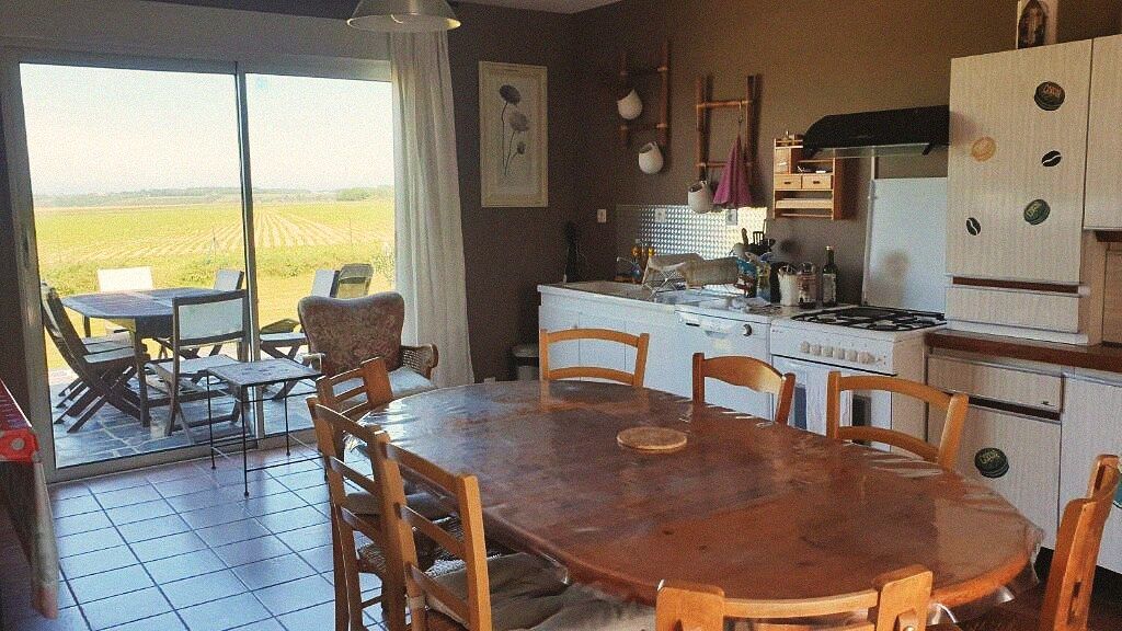 La grande cuisine de L'Alcôve de Vittefleur, table en bois et baie vitrée sur les champs